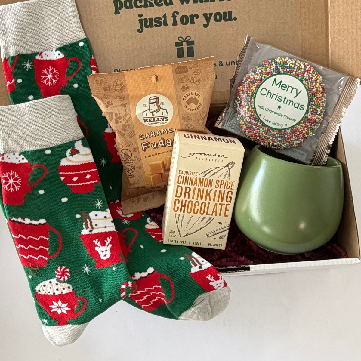 Christmas Cocoa & Cosy Toes gift box featuring festive hot chocolate socks, sage green mug, cinnamon drinking chocolate, caramel fudge and Christmas chocolate freckle.
