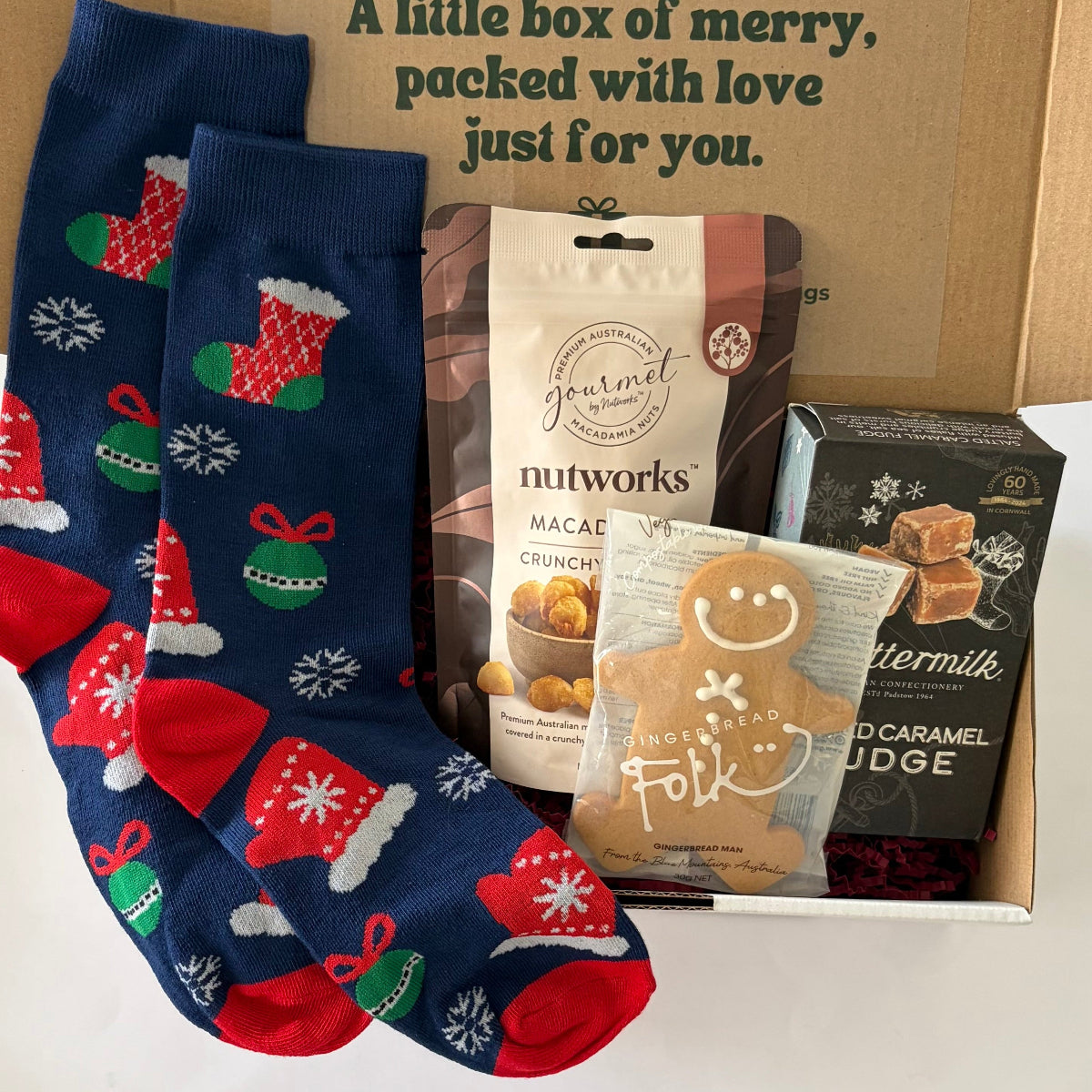 Santa's Sweet & Savoury Stash men's Christmas gift box featuring festive stocking socks, Nutworks hickory macadamias, Buttermilk salted caramel fudge and Gingerbread Folk gingerbread man in Christmas gift packaging.