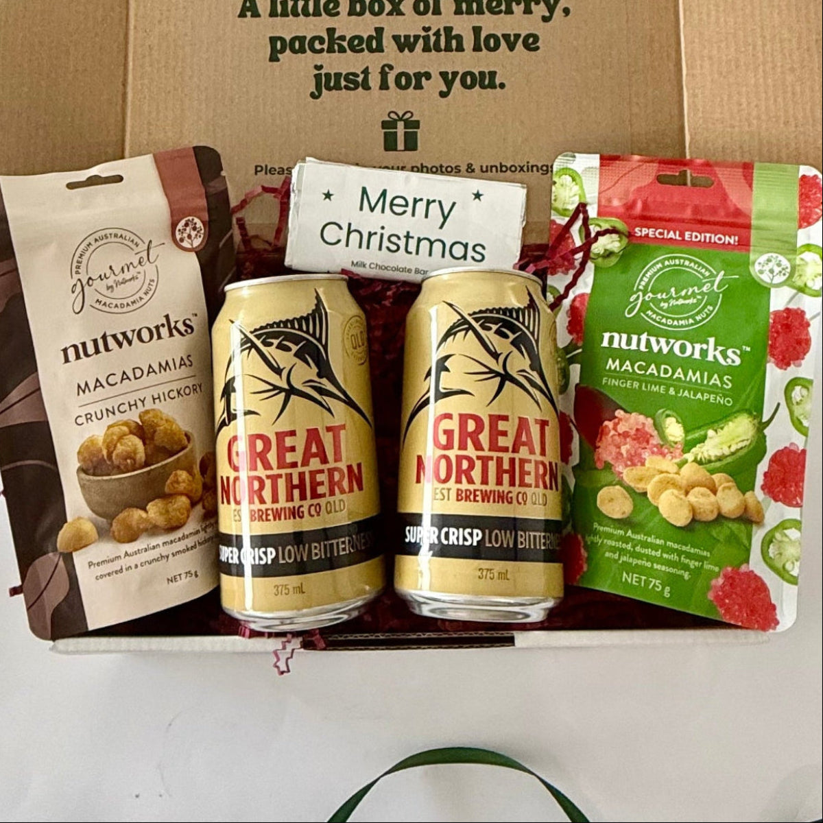Christmas Cheers Beers & Nibbles men's gift box featuring two Great Northern Super Crisp beers, Nutworks hickory and finger lime jalapeño macadamias and Merry Christmas milk chocolate.