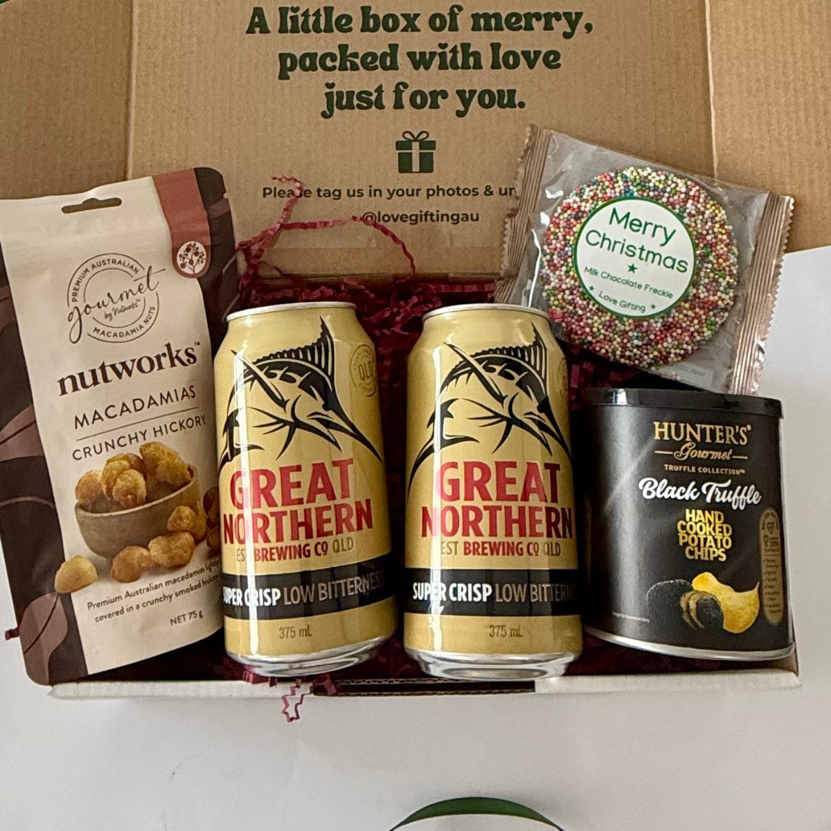 Christmas Brews & Bites men's beer gift box featuring two Great Northern Super Crisp beers, Nutworks hickory macadamias, Hunter's Gourmet black truffle potato chips and Christmas chocolate freckle.