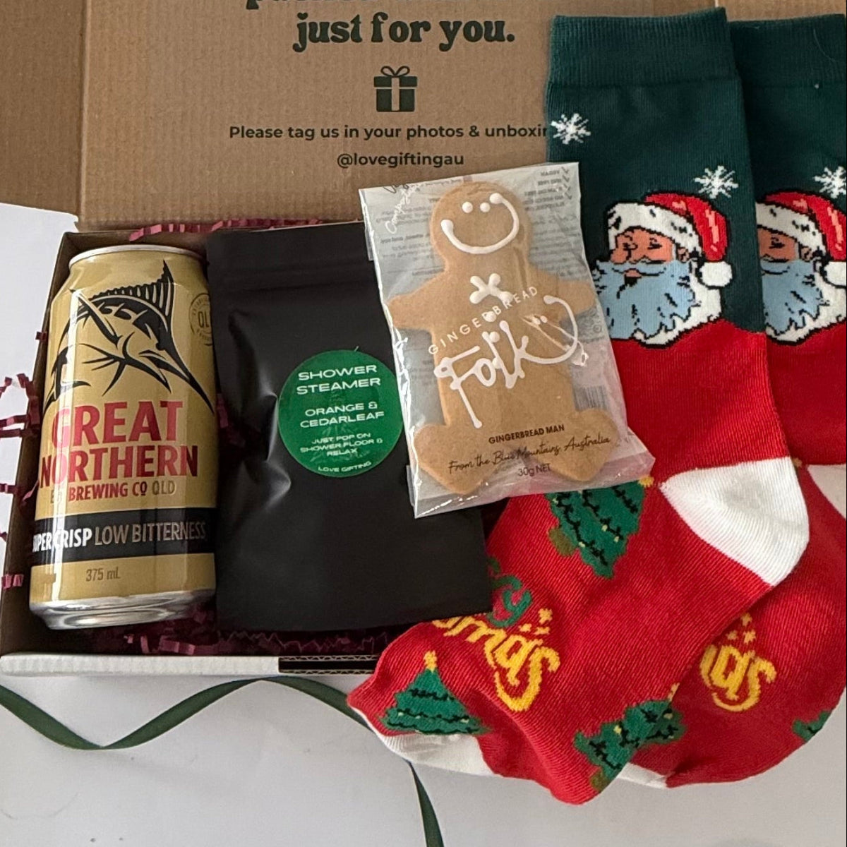 Santa's Night Off men's Christmas gift box with Great Northern beer, Santa socks, orange and cedarleaf shower steamer and gingerbread man.