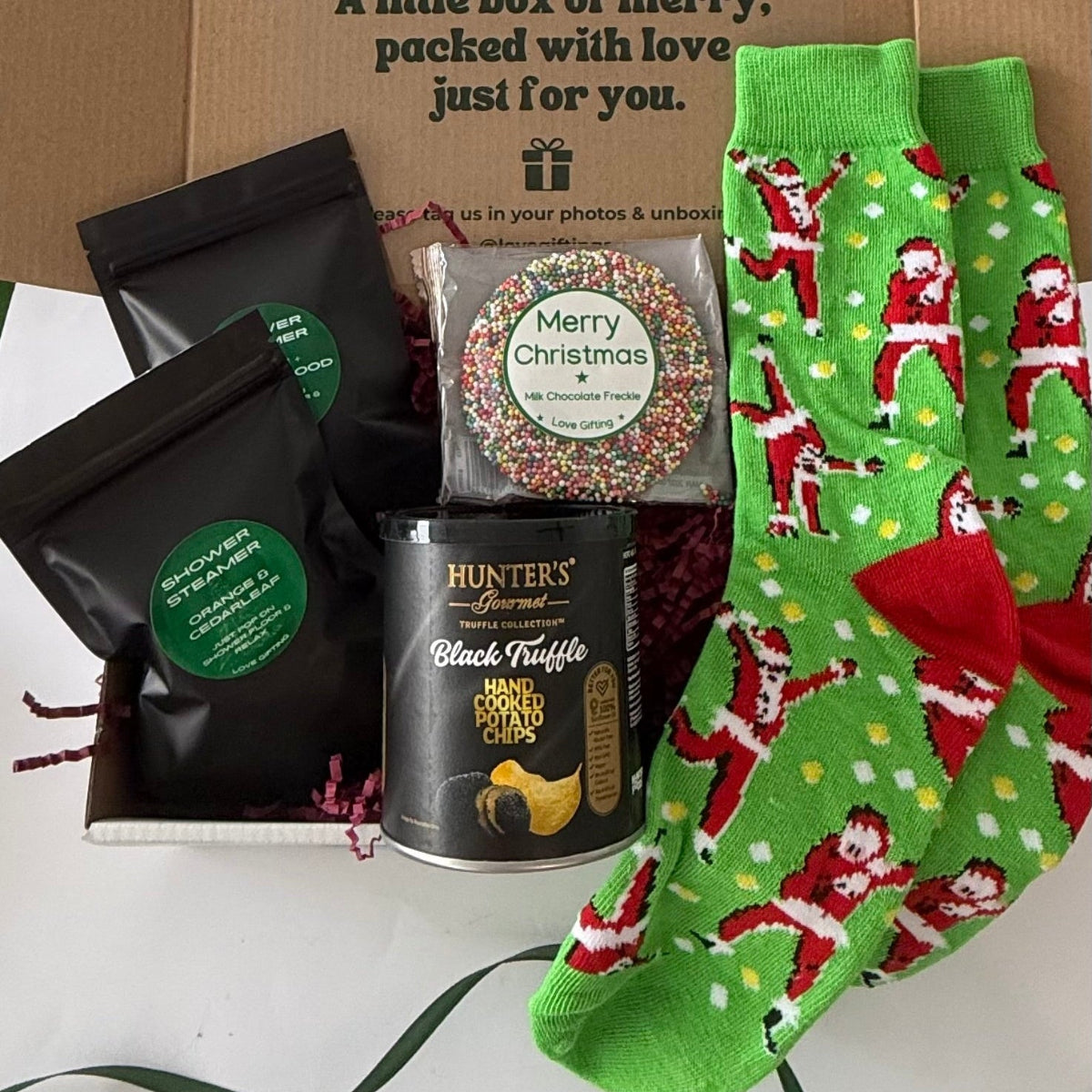 Festive Feet & Treats men's Christmas gift box with green Santa socks, Hunter's black truffle chips, Christmas chocolate freckle and shower steamers.