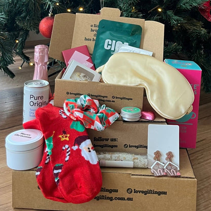Box of gifts in front of a decorated Christmas tree