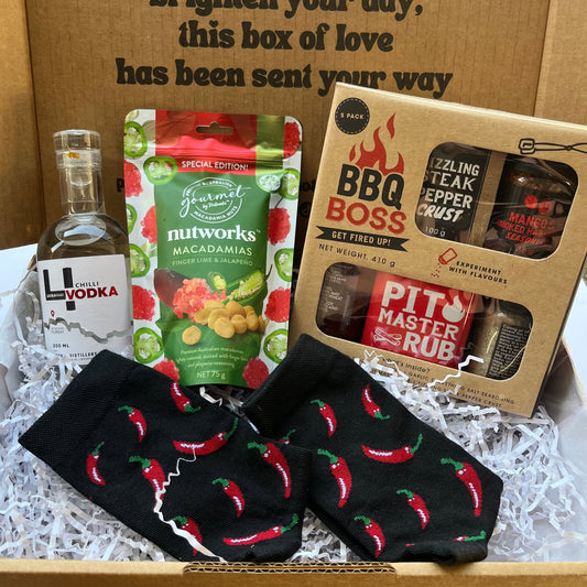 Gift box with BBQ-themed items including a bottle of vodka, macadamia nuts, and BBQ products.